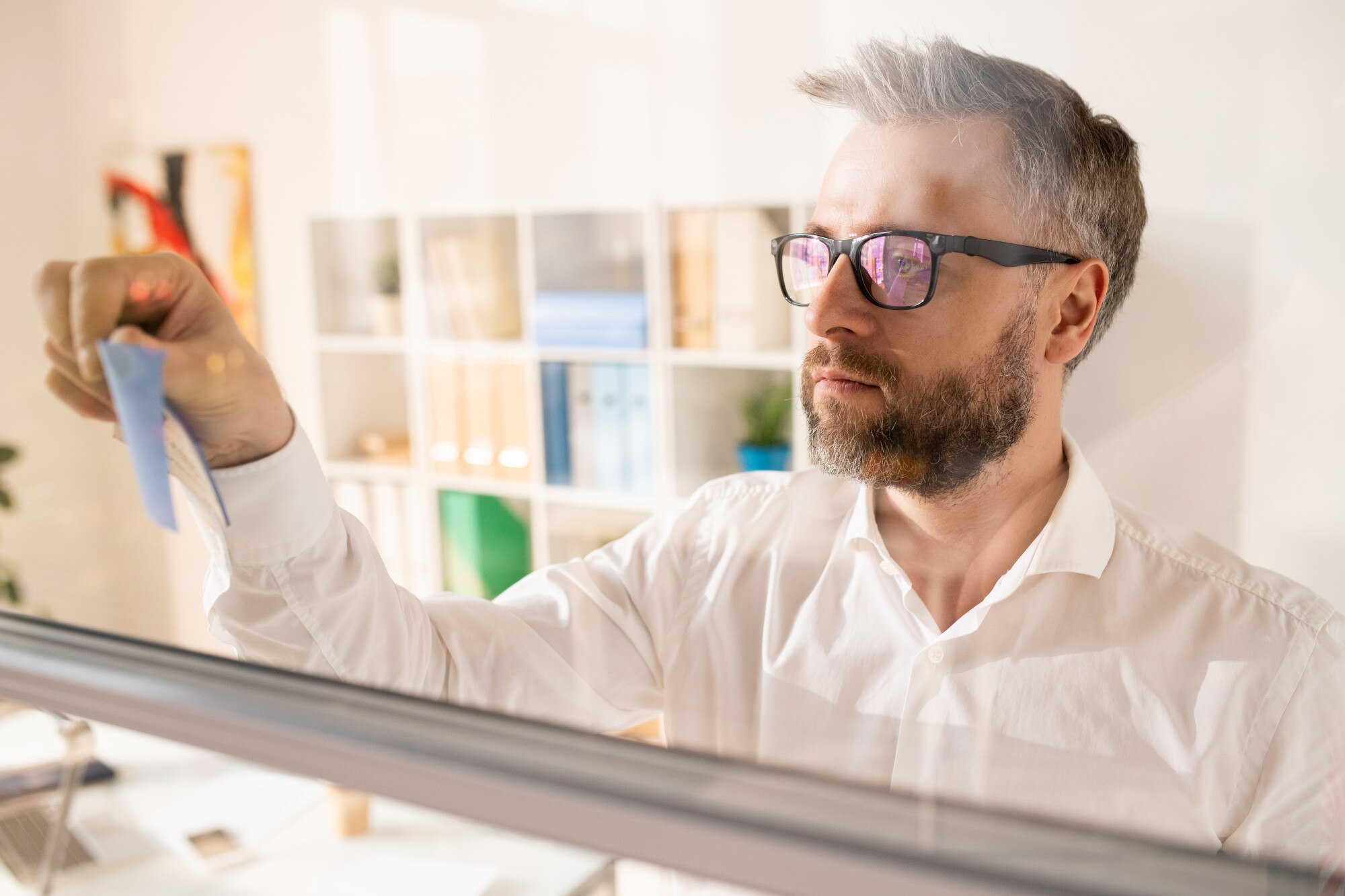 JUAN GOMEZ -  - serious manager making notes glassy board